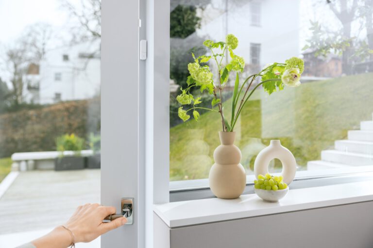 Weißer Fensterkontakt am geöffneten Fenster, daneben der kleine Magnet