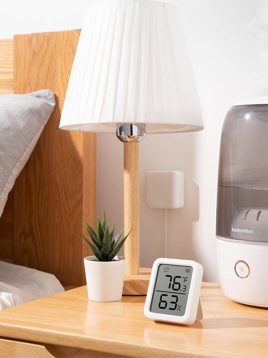 SwitchBot-Thermo-Hygrometer auf einem Nachttisch direkt neben einem Luftbefeuchter