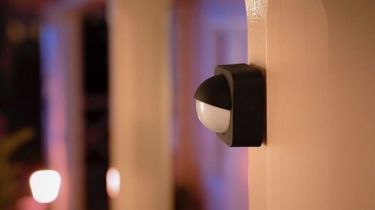 Schwarzer Philips Hue Outdoor Sensor an einem Holzpfosten